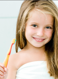 Young girl holding toothbrush, smiling at camera against white background.
