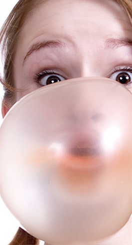 Young woman blowing a large bubble gum bubble, close-up portrait view.