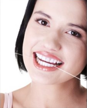 Smiling woman with dark hair wearing pink top against white background, dental or beauty advertisement.