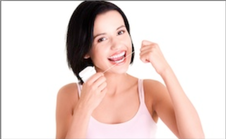 Woman flossing teeth against white background, smiling and demonstrating dental hygiene care.