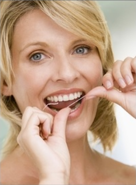 Woman flossing teeth with bright smile in dental care context.
