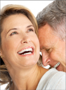 Middle-aged couple smiling together outdoors in close, affectionate pose.
