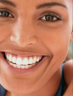 Close-up of smiling woman with bright teeth, looking directly at camera in professional headshot style.