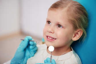 Young girl smiling during dental examination with dentist in blue gloves at clinic.