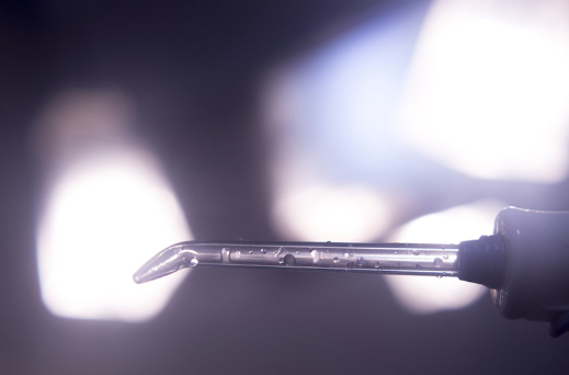 Dental instrument positioned near bright overhead surgical light in clinical setting.