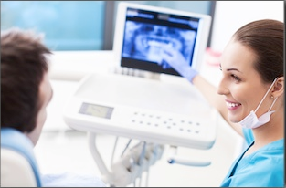 Dental professional and patient during teledentistry consultation with monitor displaying oral examination.