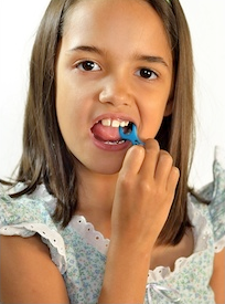 Young girl holding colorful candy near mouth against white background.