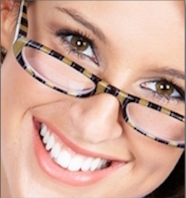 Woman wearing plaid-framed glasses smiling at camera, close-up portrait shot.