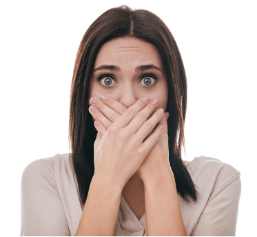 Woman with shocked expression covering mouth with hands against white background.