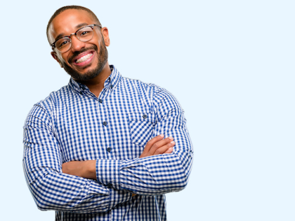 Professional man in blue checkered shirt with crossed arms, smiling against light blue background.