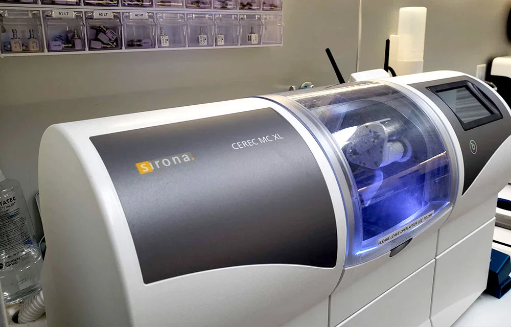 Laboratory automated analyzer machine with blue illuminated chamber in medical facility setting.