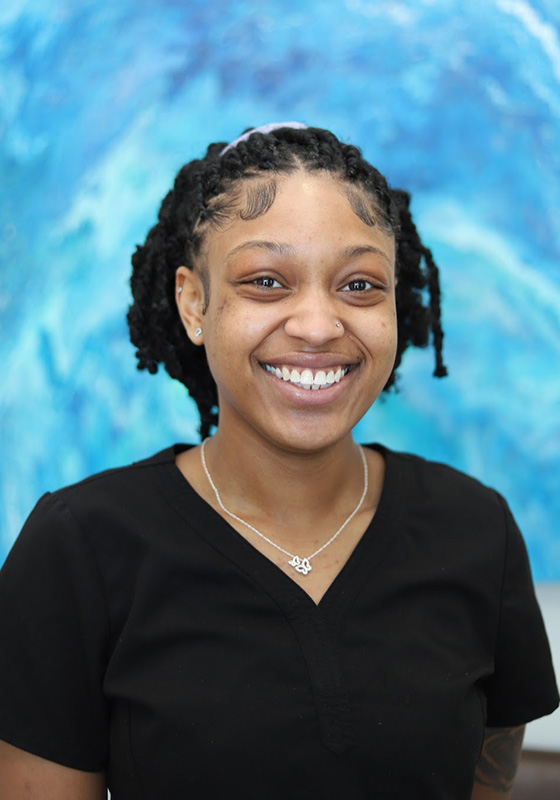 Smiling young woman in black v-neck shirt against blue water background portrait.