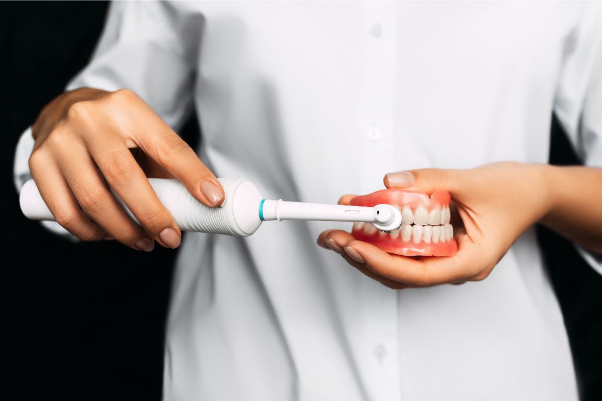 Dental professional demonstrating proper toothbrush technique on model teeth