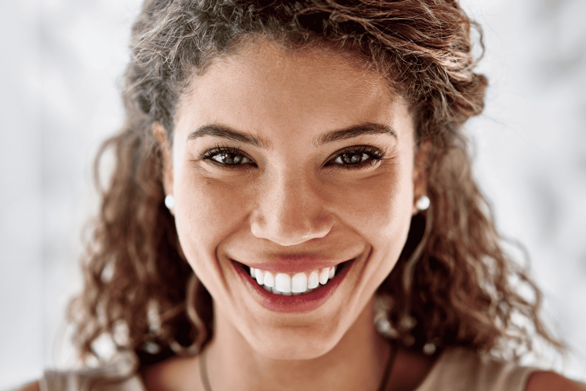 Close up of woman with curly hair smiling showing white teeth